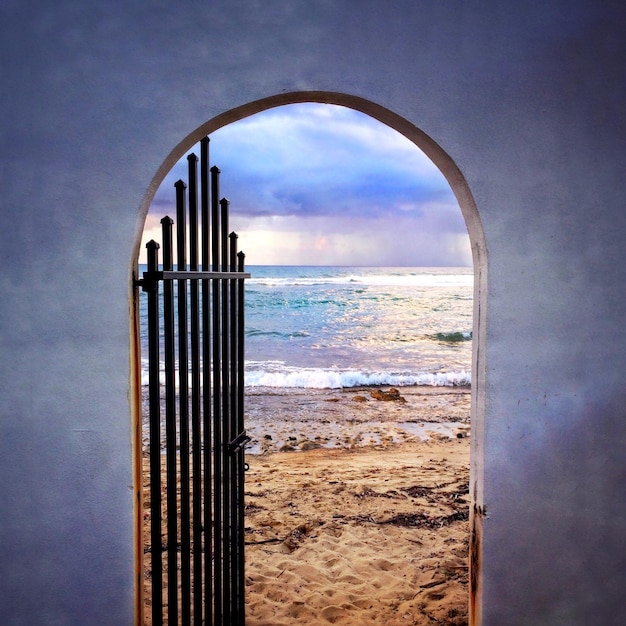 Scenic view of beach against cloudy sky seen from archway