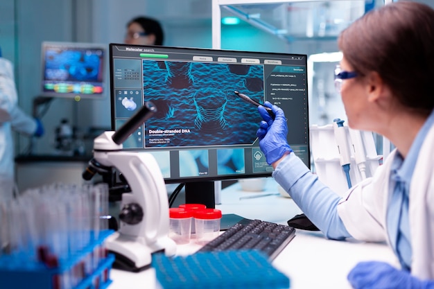 Scientist in biochemistry industry healthcare analysing virus on computer monitor, pharmacology. Chemistry research and analysing in science medicine lab developing and stying new type of vaccin.