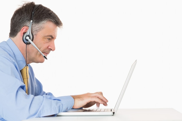Serious man with headset typing on laptop