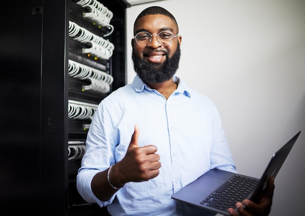 Server room laptop and thumbs up with technician man for internet connection and software programming Engineer black person with technology and thank you for cybersecurity system in data center