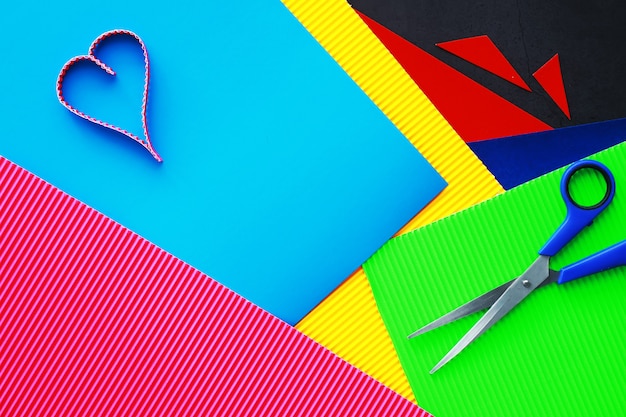 Sheets of colored paper, iridescent palette of colored paper, rainbow colors. Top view on table with colored paper and scissors.