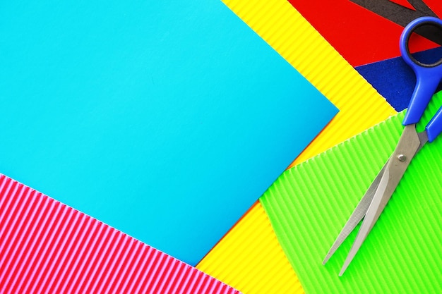 Sheets of colored paper, iridescent palette of colored paper, rainbow colors. Top view on table with colored paper and scissors.