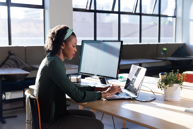 Side view of african american young businesswoman using laptop in office