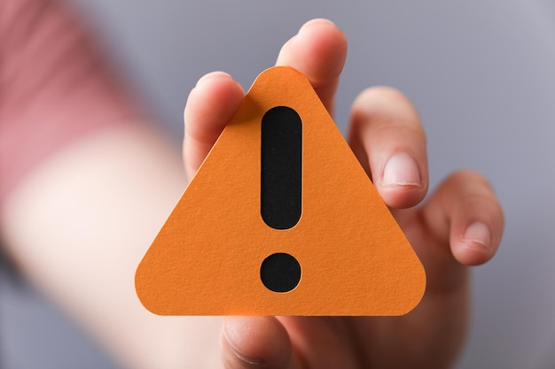 sign of the exclamation mark on a yellow paper in the hands of a man