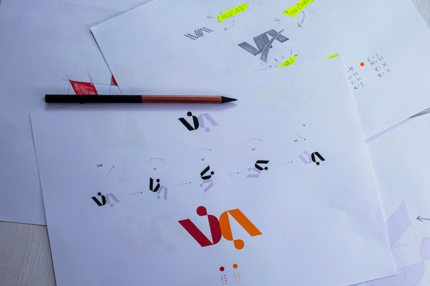 sketches and drawings of the logo printed on paper. development of logo design in the studio on a table.