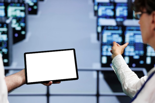 Skillful system administrators using mock up tablet to check supercomputers close up Devices in computer network security server hub providing processing and memory resources for several workloads