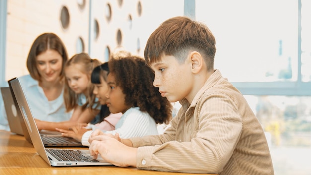 Smart boy playing laptop with multicultural friend learning prompt erudition
