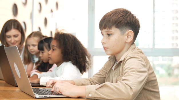 Smart boy playing laptop with multicultural friend learning prompt erudition