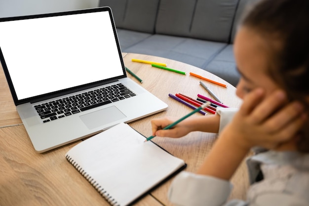 Smart little little girl learns online on a laptop, video chat at home, distant education concept