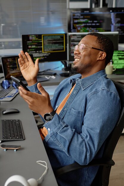 Smiling black male programmer joyfully clapping hands