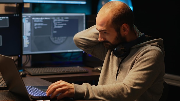 Software developer dealing with spinal discomfort and working on server programming, sitting at office. Suffering from back pain and coding database system, stressed male coder.