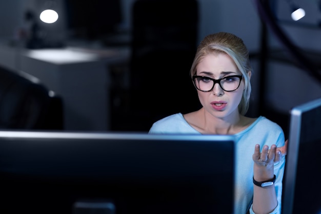 Something went wrong. Young pleasant shocked programmer sitting in the office and using computers while working and expressing emotions