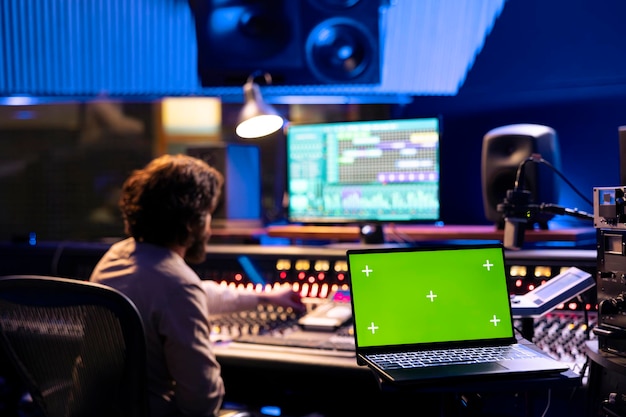 Sound engineer working on control desk with greenscreen layout