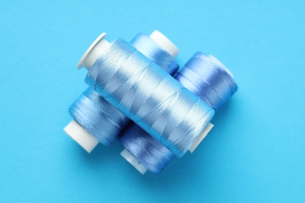 Spools of sewing threads on light blue background top view