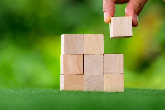 Stacking blank wooden cubes on green background with copy space for input wording and infographic icon Empty brown wooden object block for symbol icon put technology zero gravity business concept