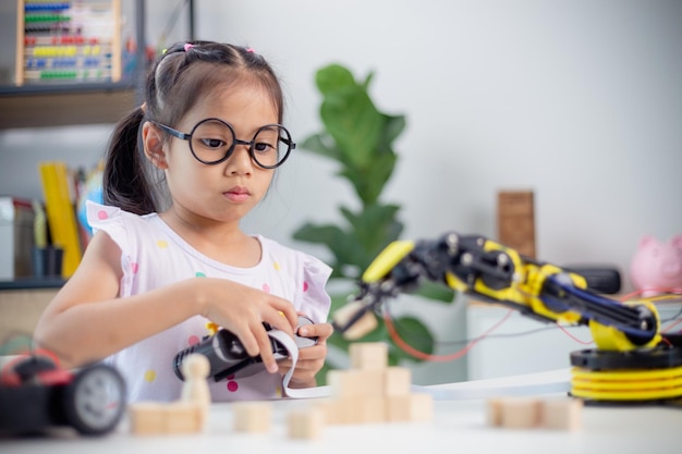 STEM education concept Asian students learn at home by coding robot arms in STEM mathematics engineering science technology computer code in robotics for kids concepts