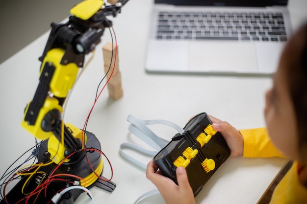 STEM-koulutuskonsepti. Aasialaiset opiskelijat oppivat kotona koodaamalla robottikäsiä STEM-matematiikassa, insinööritieteissä, luonnontieteissä, teknologiassa, tietokonekoodissa robotiikassa lasten konsepteja varten