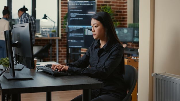 System engineer focused on writing code sitting at desk in software development office while team of coders are developing cloud computing app. Programer concentrating on creating algorithm.