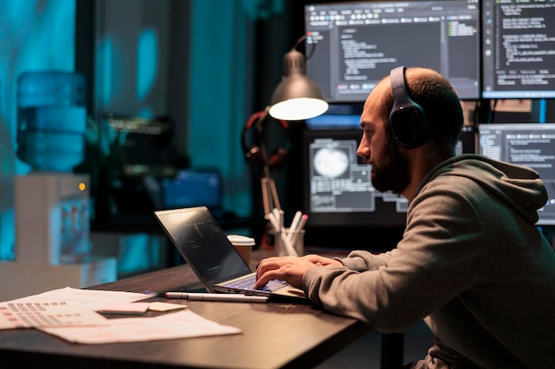 System engineer programming user interface on computer and compiling source code with html script and algorithms. Coding cloud computing online program on multiple screens at night.