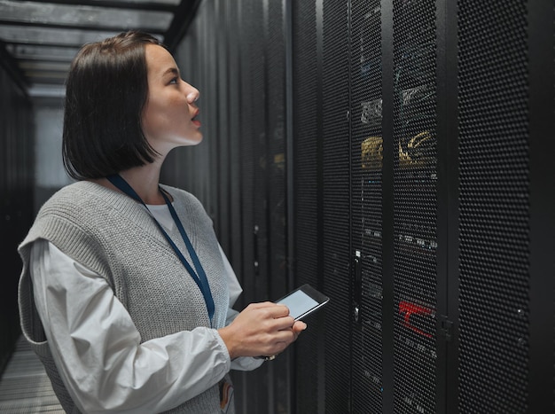 Tablet server room and big data with a programmer asian woman at work on a computer mainframe Software database and information technology with a female coder working alone on a cyber network