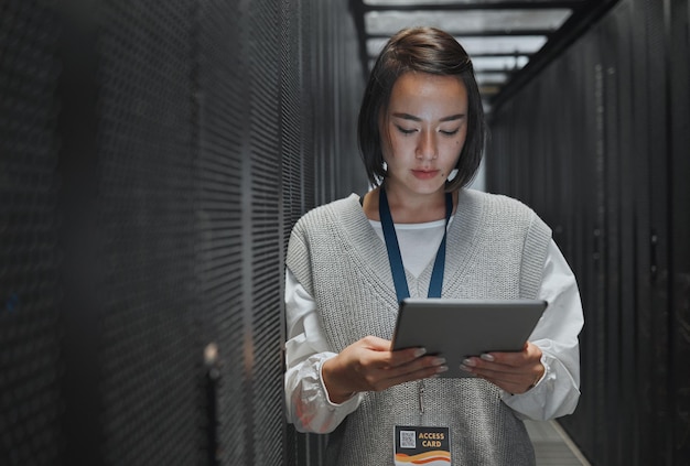 Tablet server room and cloud computing with a programmer asian woman at work on a mainframe Software database and information technology with a female coder working alone on a cyber network