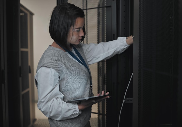 Tablet server room and engineering with a programmer asian woman at work on a computer mainframe Software database and information technology with a female coder working alone on a cyber network