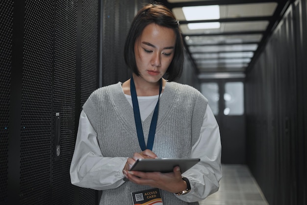 Tablet server room and networking with a programmer asian woman at work on a computer mainframe Software database and information technology with a female coder working alone on a cyber network