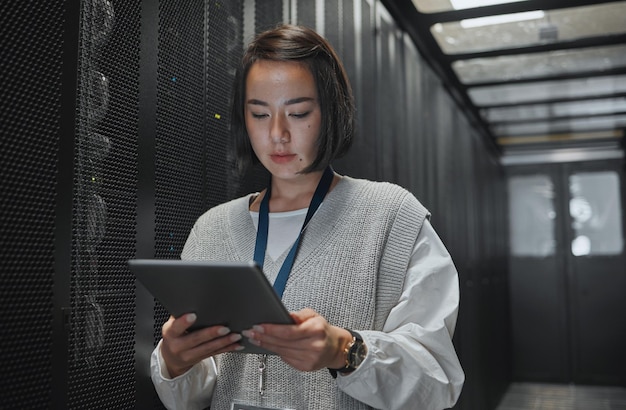 Tablet server room and security with a programmer asian woman at work on a computer mainframe Software database and information technology with a female coder working alone on a cyber network