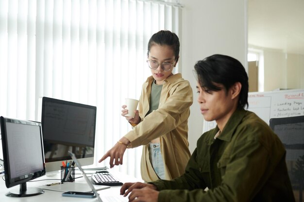 Team leader pointing out mistake in programming code of coworker