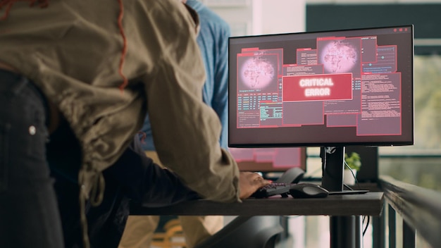 Team of software developers dealing with security breach and hacked it system on multiple computers. Programmers encountering hacking error and cyber crime alert. Handheld shot.