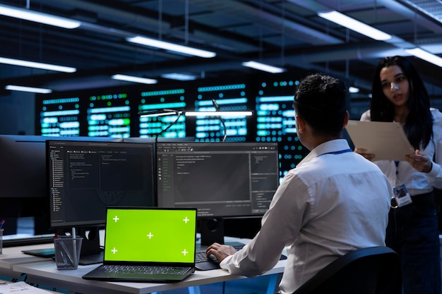 Teamworking technicians in server room using green screen laptop