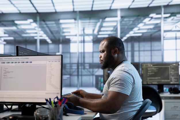technician at desk writing code and doing checkup on server room