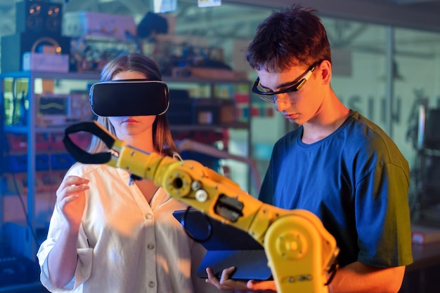 teens doing experiments in robotics in a laboratory boy in protective glasses using tablet and girl