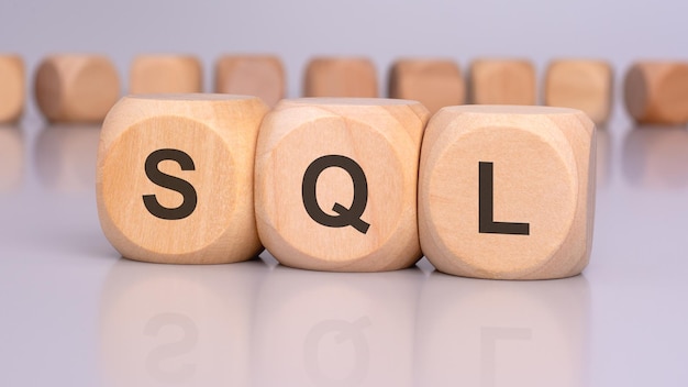 three wooden blocks with the letters SQL in focus reflecting on the table surface