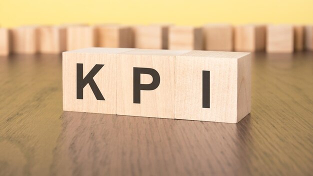three wooden cubes on a yellow background with the abbreviation KPI Key Performance Indicators