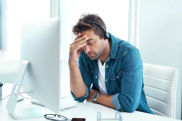 Tired headset and man with stress headache and mental health of person exhausted and customer service in office Mic frustrated and thinking in call center desk and telemarketing with migraine