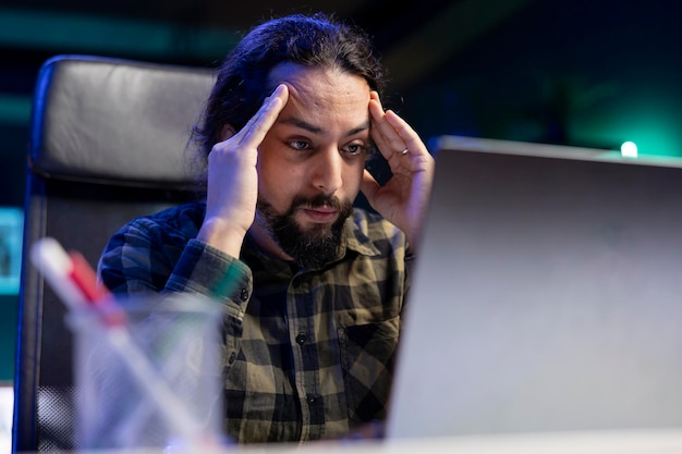 Tired man looking at his laptop