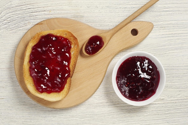 Toasted bread with jam on rustic wooden table, top view