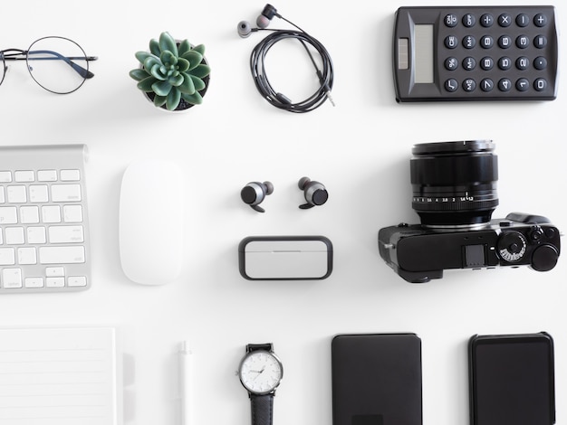 top view of office desk table with  calculator, notebook, plastic plant, smartphone and keyboard on white