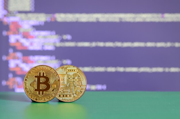 Two gold bitcoins lie on the green surface