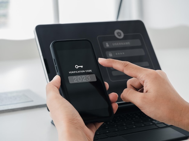Two steps authentication or 2FA concept 2023 Verification code with key icon on smart phone screen in hand with laptop for validate password page Identity verification cyber security technology