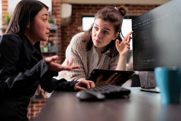Unsure asian programming expert asking colleague about generated bug report file. Blockchain developing engineer using high technology software to defend database system.
