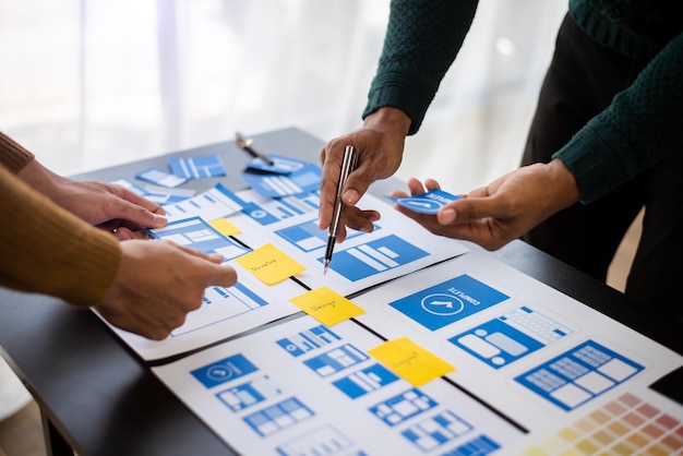 UX developer and ui designer brainstorming about mobile app interface wireframe design with customer breif and color code at modern office