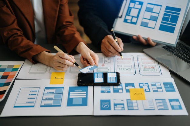 UX developer and ui designer brainstorming about mobile app interface wireframe design with customer breif and color code at officexA