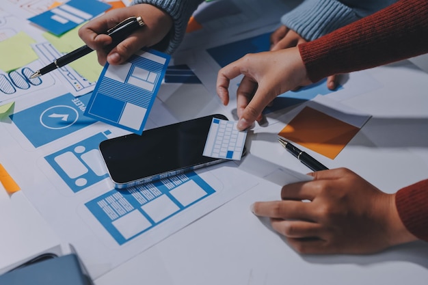 UX UI designer testing prototype on a phone discussing and brainstorming on wireframes for a website and mobile app prototype in the concept of website and mobile application design concept