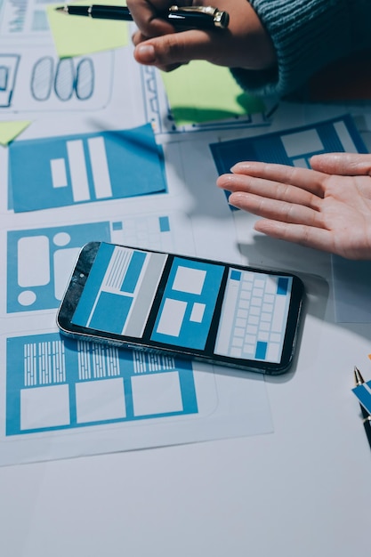 UX UI designer testing prototype on a phone discussing and brainstorming on wireframes for a website and mobile app prototype in the concept of website and mobile application design concept