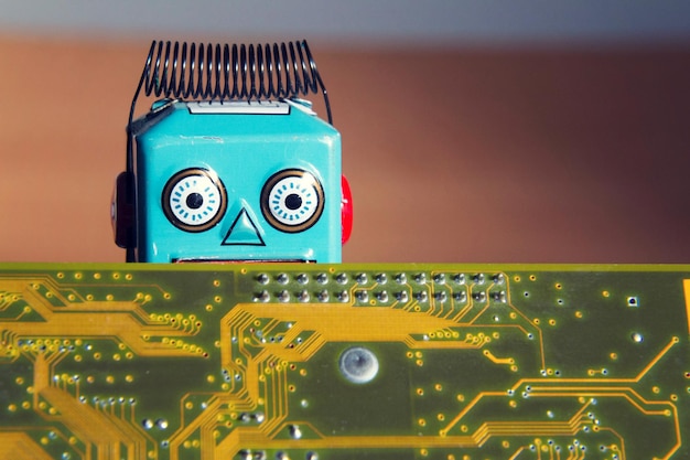 Vintage tin toy robot behind computer board artificial intelligence concept