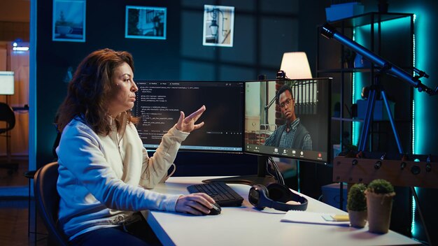 Woman doing software debugging helped by coworker in videocall