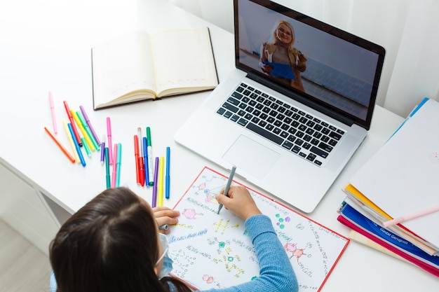 Woman video conferencing with tutor on laptop at home. Distance education concept.