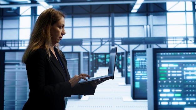 Woman walking in high tech facility using laptop to patch network issues